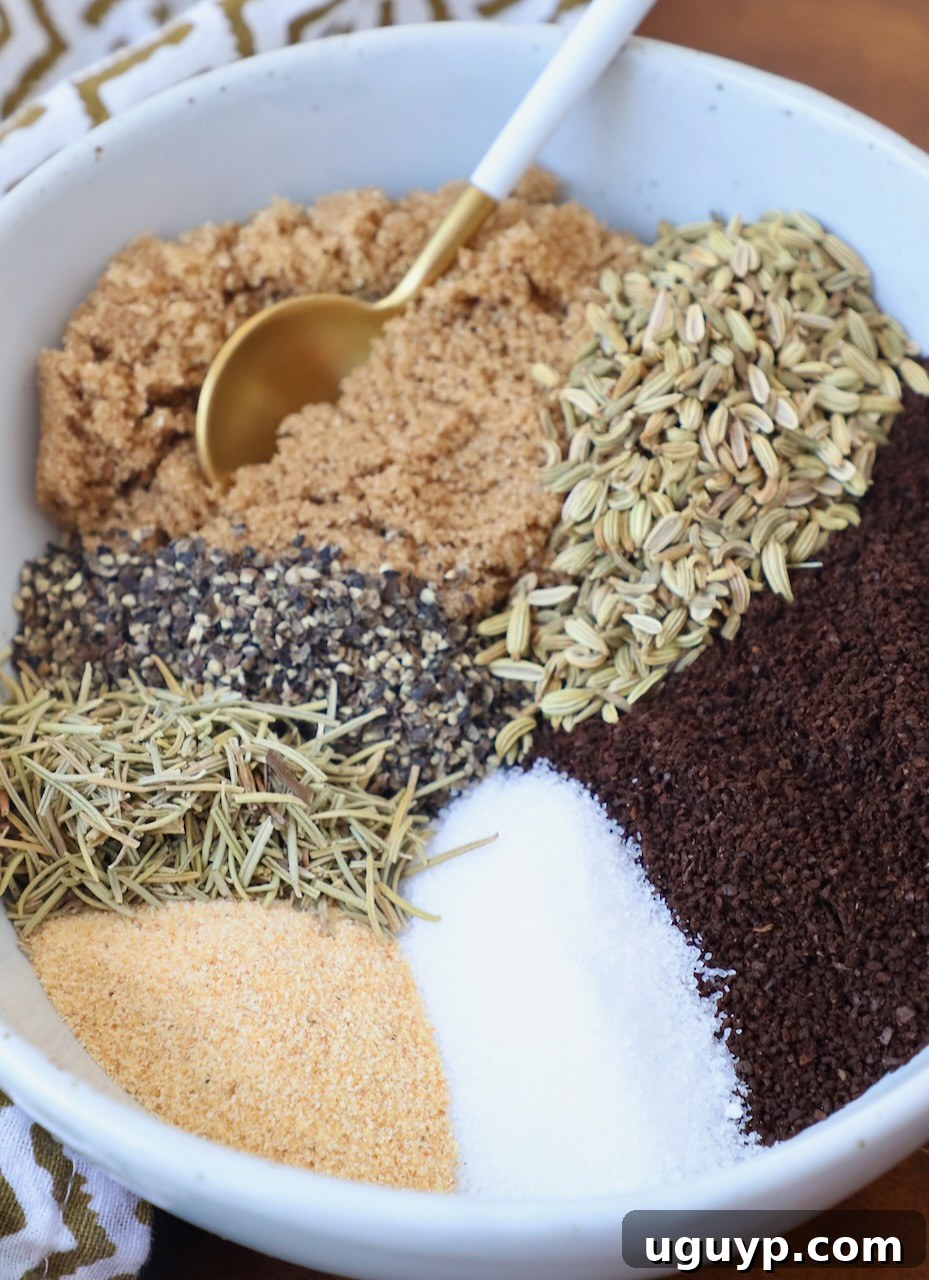 Individual ingredients for the coffee steak rub, including ground coffee, brown sugar, and a variety of herbs and spices, are displayed separately in a bowl with distinct sections, alongside a small spoon.