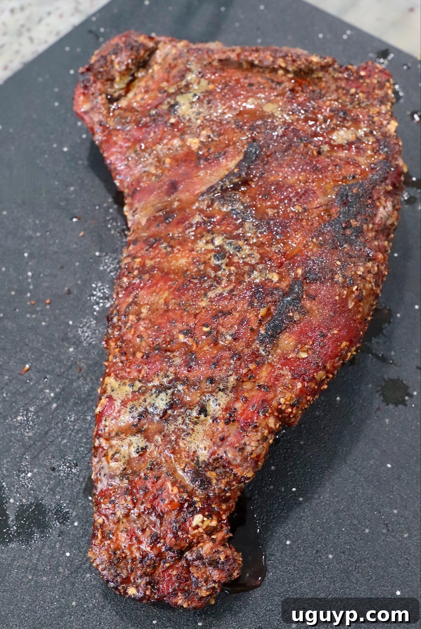 Finished smoked and seared tri tip roast resting on a cutting board, ready to be sliced after its crucial resting period.