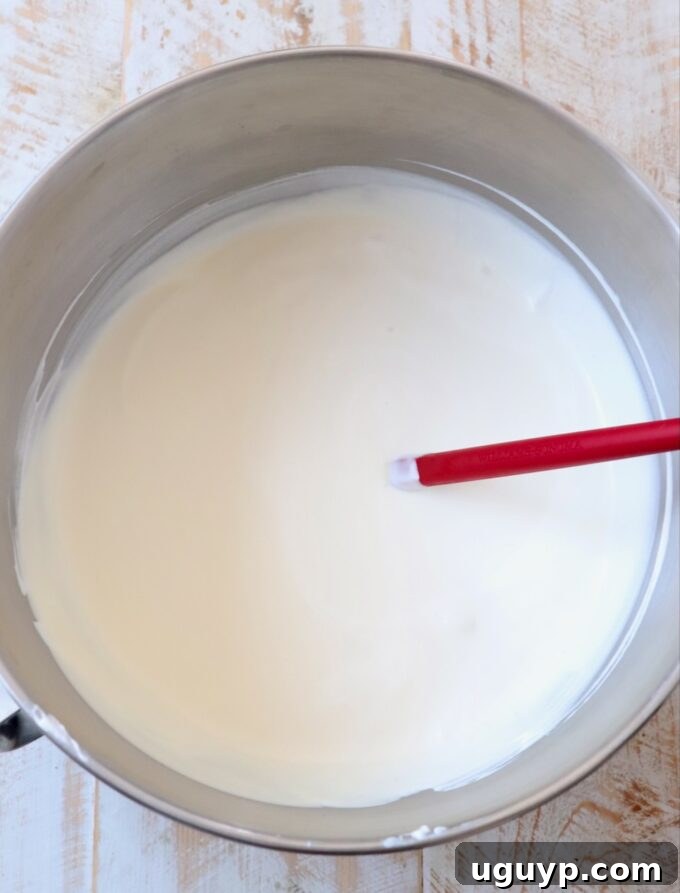 Freshly whipped heavy cream in a large mixing bowl with a red spatula