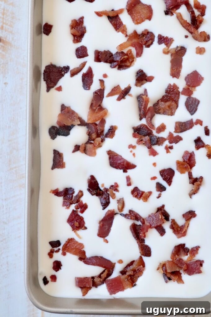 Maple bacon ice cream base poured into a metal container and topped with reserved candied bacon pieces