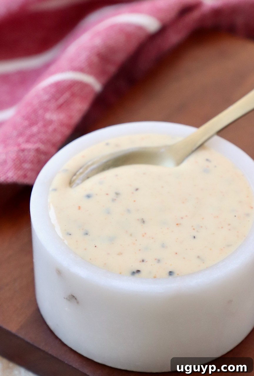 Creamy White BBQ Sauce in a small white bowl with a spoon, ready to be served with grilled or smoked meats.