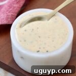 White BBQ Sauce in a small bowl with a spoon, showing its creamy texture.