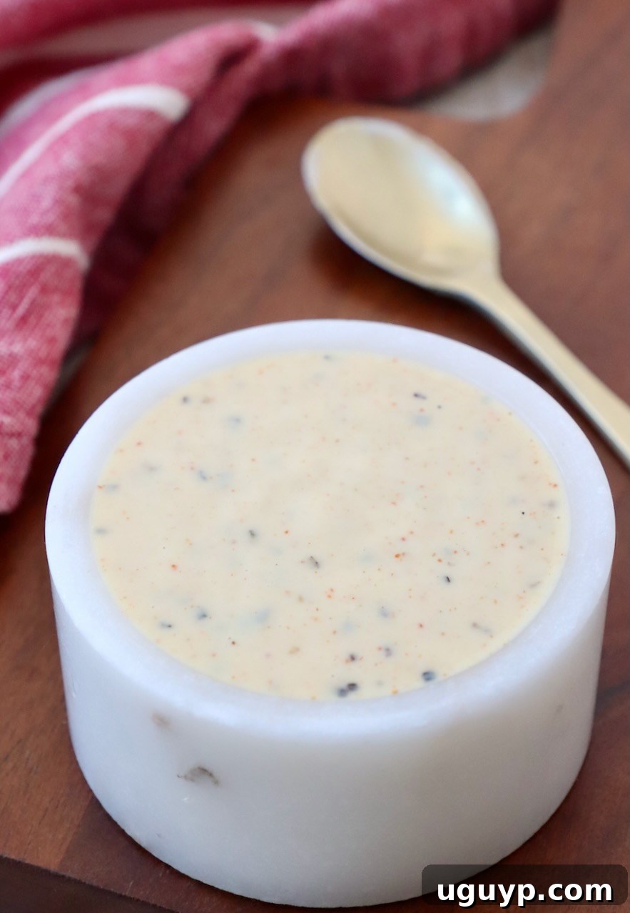 A small white bowl filled with creamy Alabama White BBQ Sauce, ready for serving.
