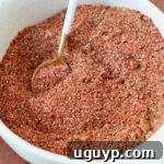 A bowl of homemade BBQ seasoning blend with a small spoon, ready for cooking.