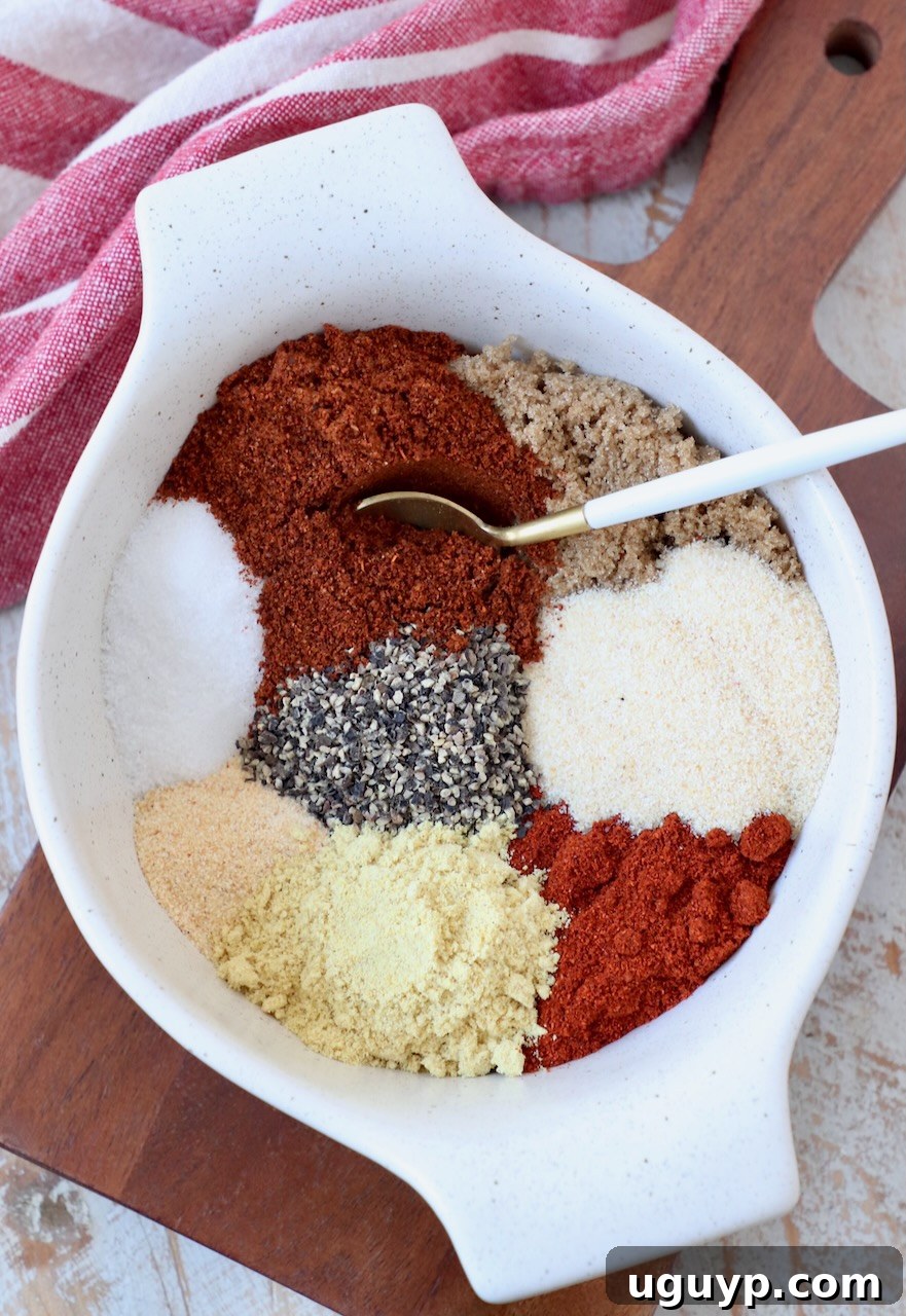 Individual spices neatly separated in a bowl before being mixed to create the BBQ seasoning, with a small spoon ready to combine them.