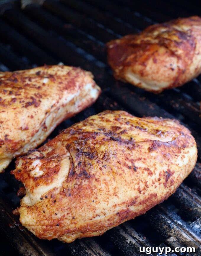 BBQ chicken pieces steadily cooking on the grill, surrounded by smoky heat.