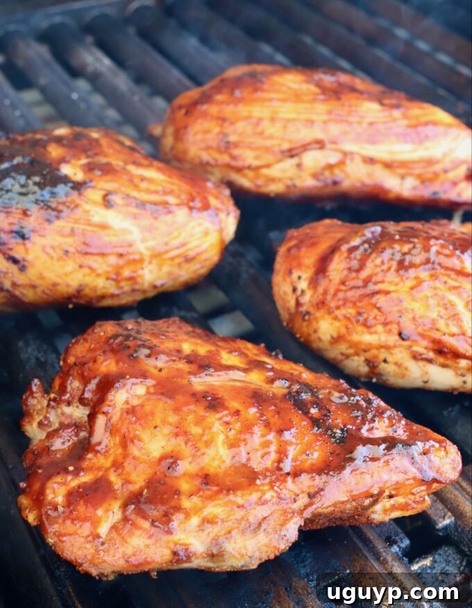 Chicken breasts, now coated in BBQ sauce, searing over direct heat on the grill, developing a delicious glaze.
