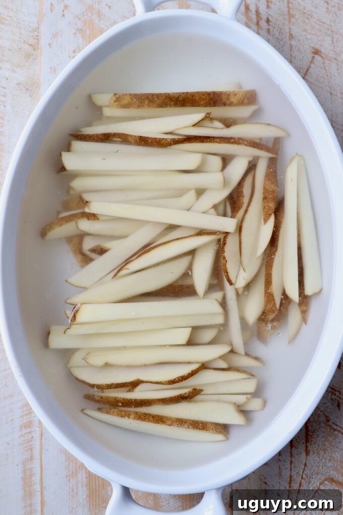 sliced potatoes soaking in casserole dish filled with water