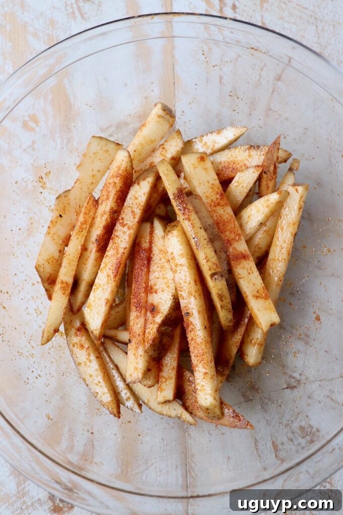 uncooked seasoned fries in glass bowl