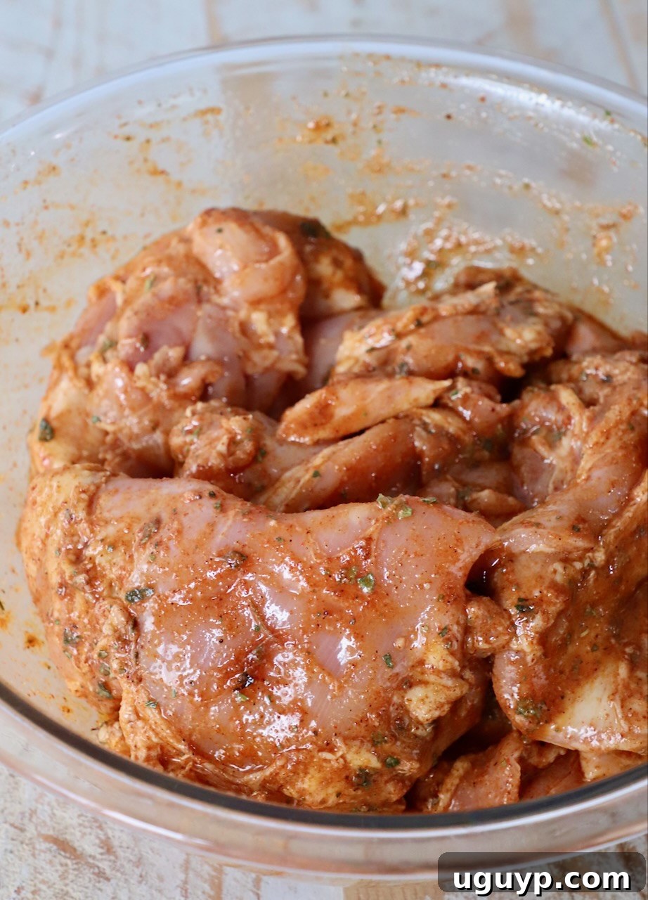 raw chicken thighs covered in marinade in large glass bowl