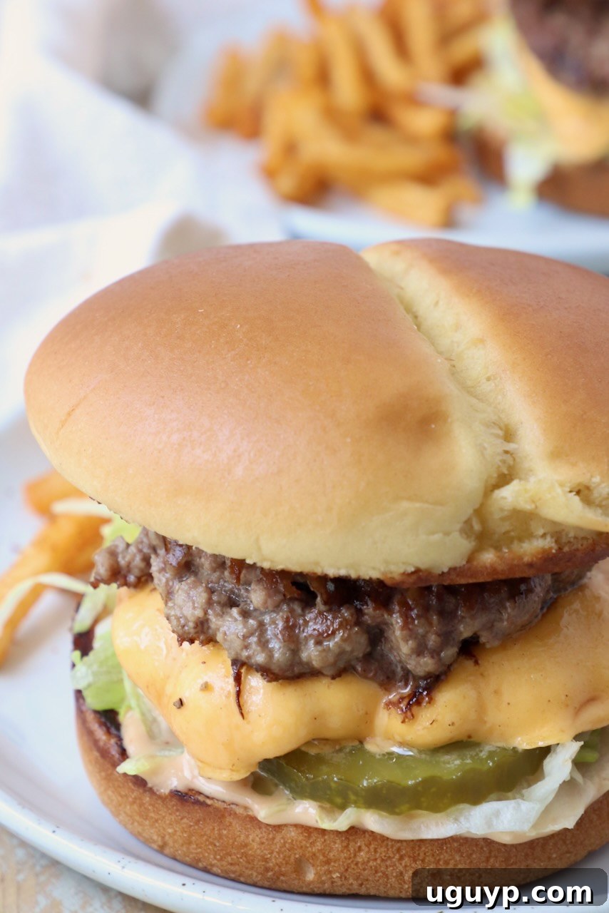 A perfectly cooked smash burger with melted cheese, lettuce, and sauce, served on a toasted bun on a plate.