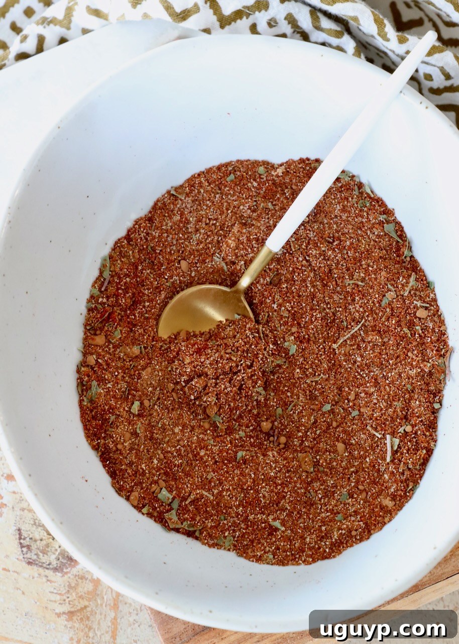 A bowl of homemade enchilada seasoning with a spoon, ready for use, capturing the texture and color of the spice blend
