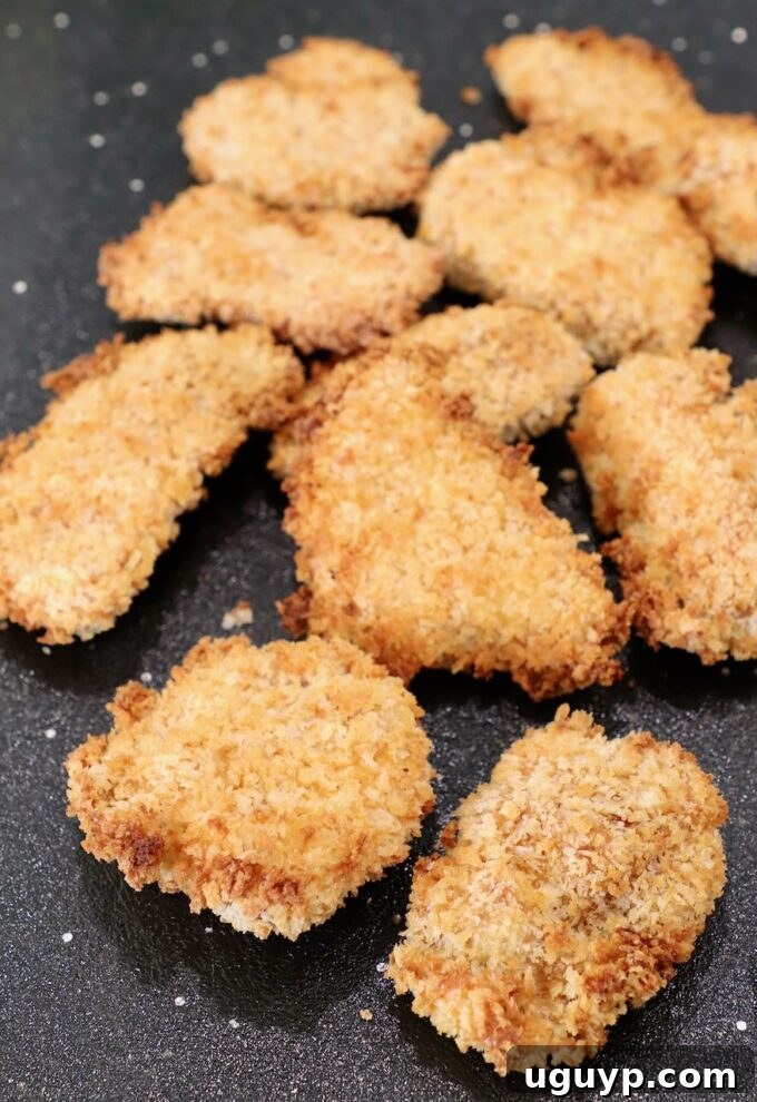 crispy pieces of cooked chicken on a wooden cutting board, golden brown and ready to be sauced