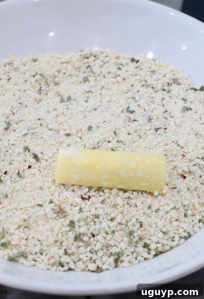 piece of mozzarella on top of seasoned breadcrumbs in bowl