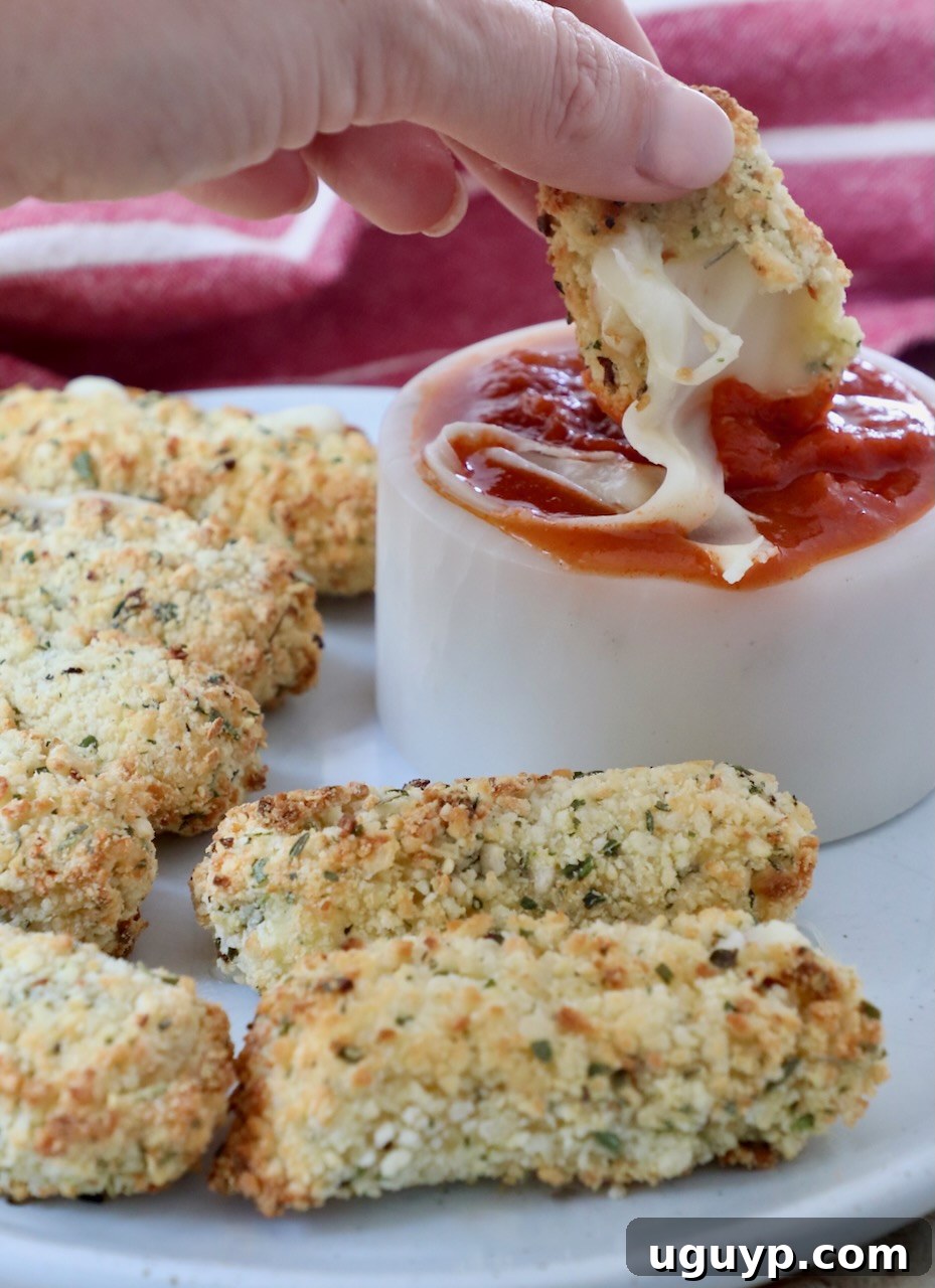 mozzarella sticks on plate and dipped into bowl of marinara sauce