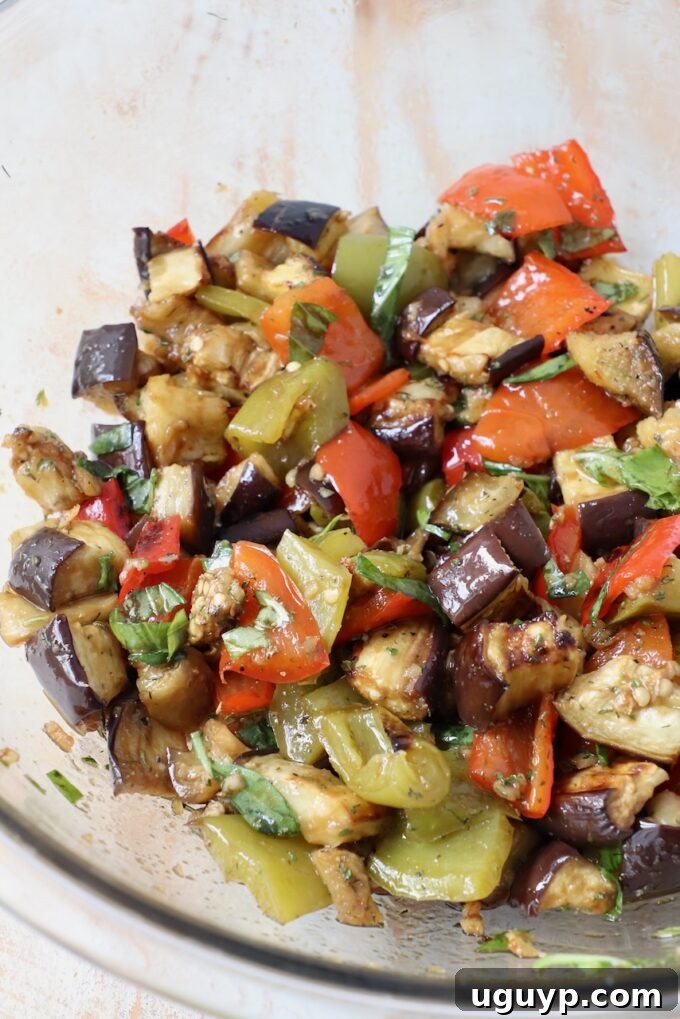 roasted eggplants and bell peppers tossed with balsamic dressing in large glass bowl
