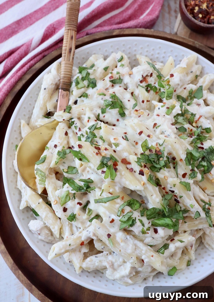Cooked garlic parmesan chicken pasta in a bowl, topped with fresh chopped green onions for garnish.