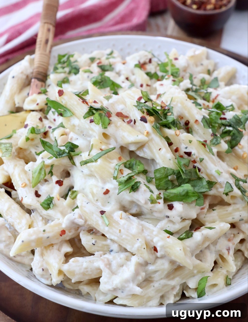 Creamy chicken pasta in a bowl with a serving spoon, garnished lightly and ready to be enjoyed.