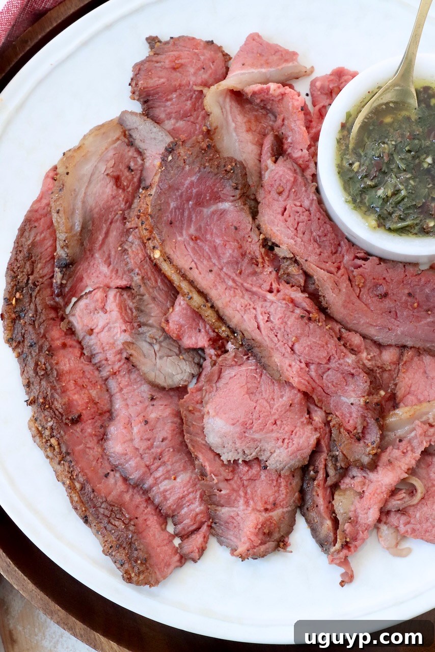Thinly sliced picanha steak on a large plate, ready to serve, with a small bowl of herb butter sauce on the side.