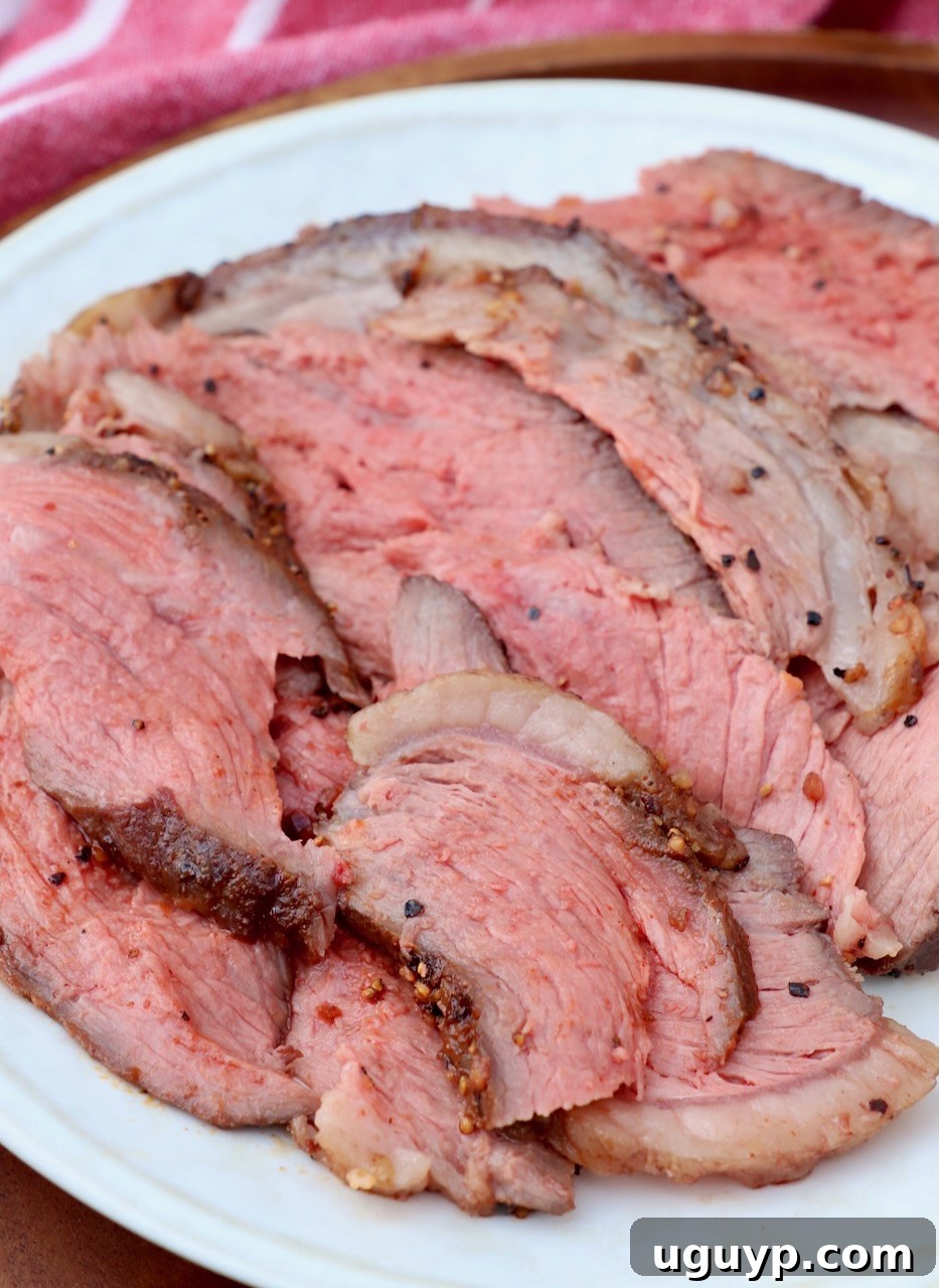 Thin slices of cooked picanha steak arranged artfully on a white plate, showcasing the fat cap.