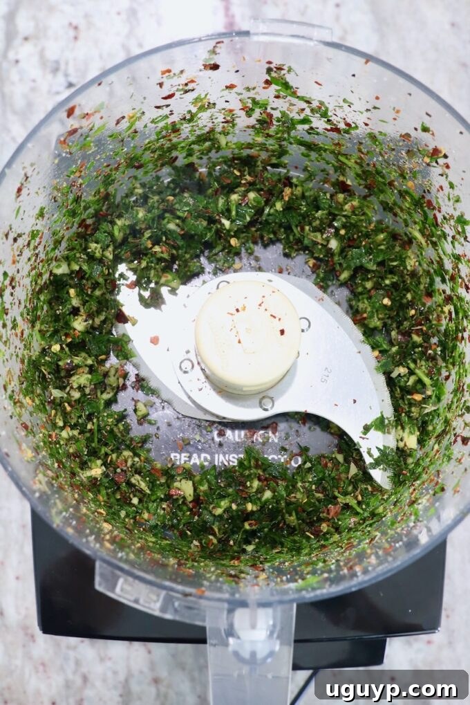 Finely chopped fresh herbs and garlic in a food processor, ingredients for the herb butter sauce.