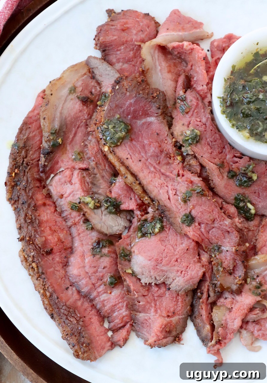 Thinly sliced cooked picanha steak on a plate, generously drizzled with herb butter sauce, ready to be served.