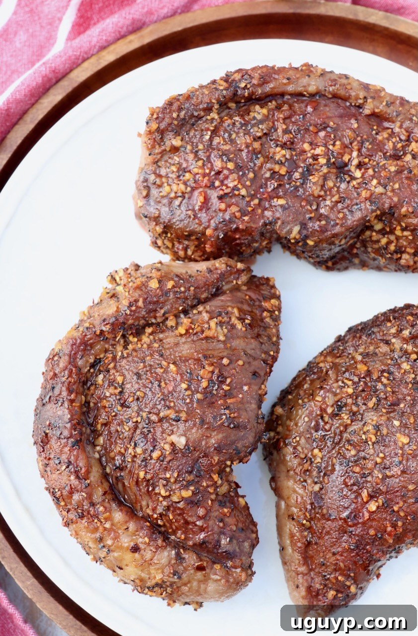 Cooked picanha steaks, one whole and one sliced, presented on a rustic plate.