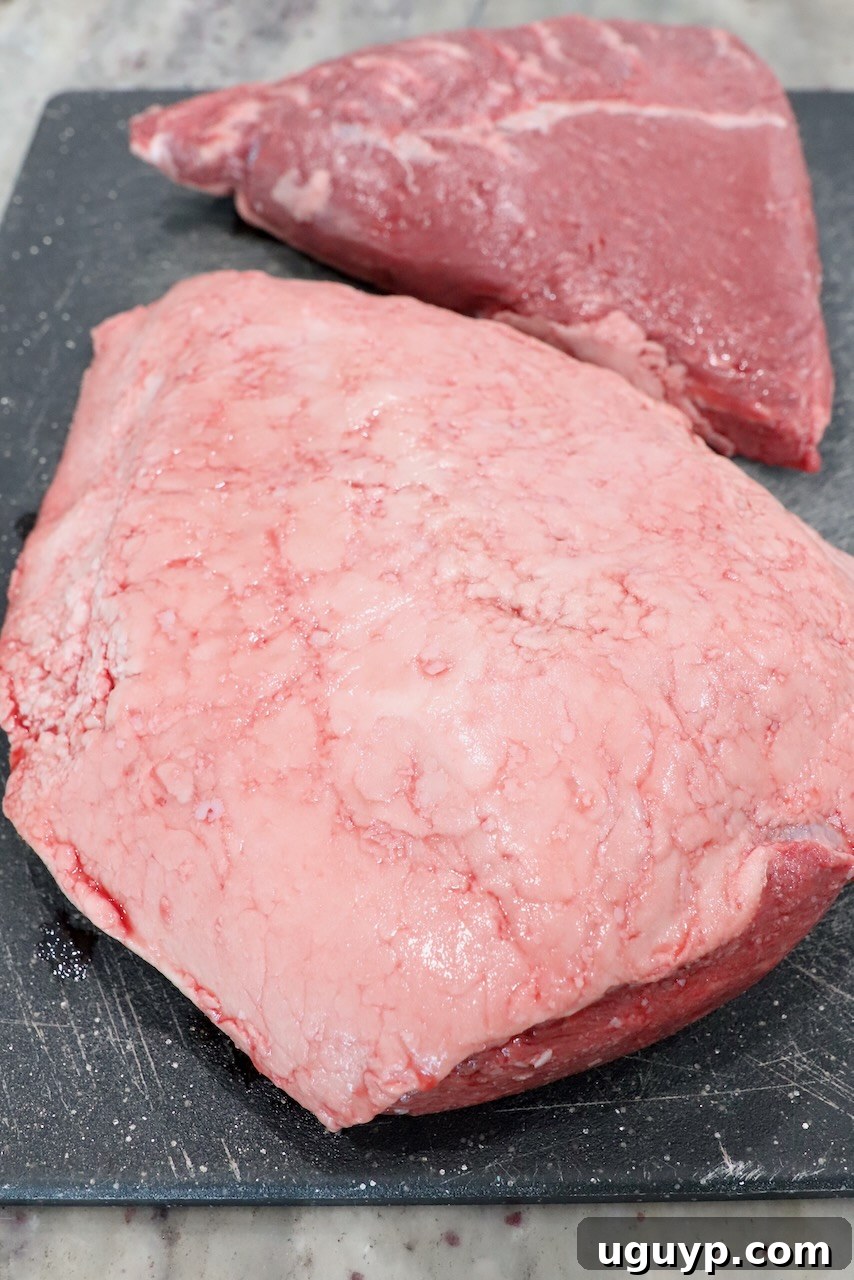 Uncooked picanha roast with the fat cap visible, sitting on a cutting board, ready for slicing.