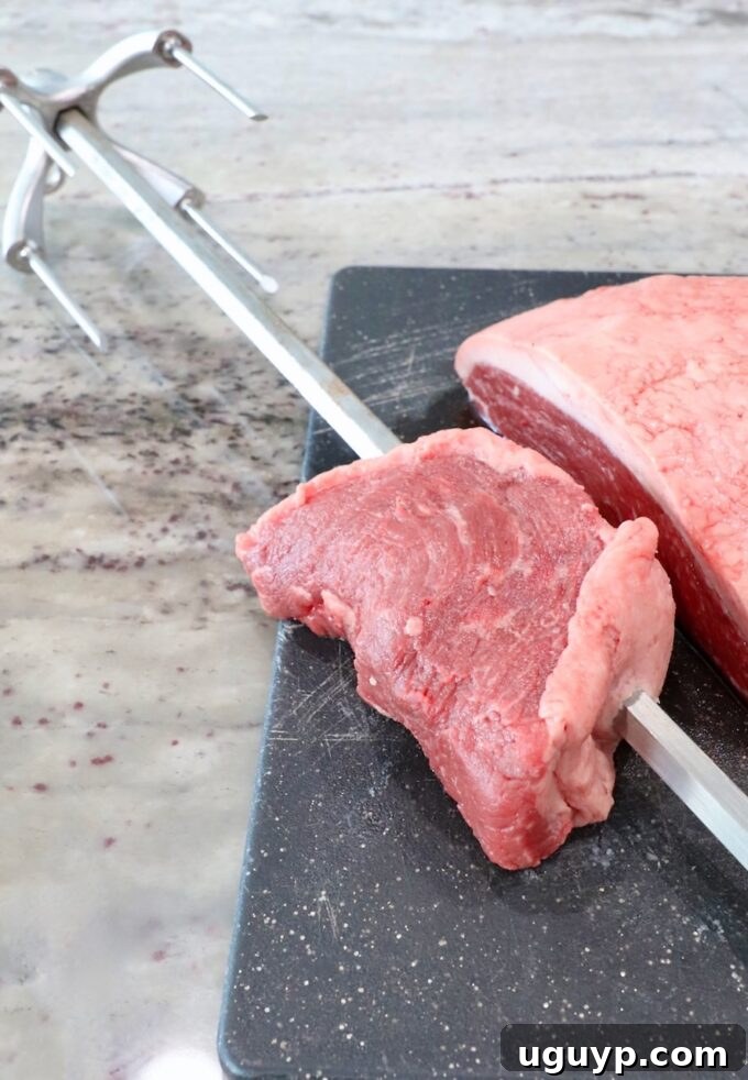 Three slices of picanha steak arranged in a C-shape on a rotisserie rod.