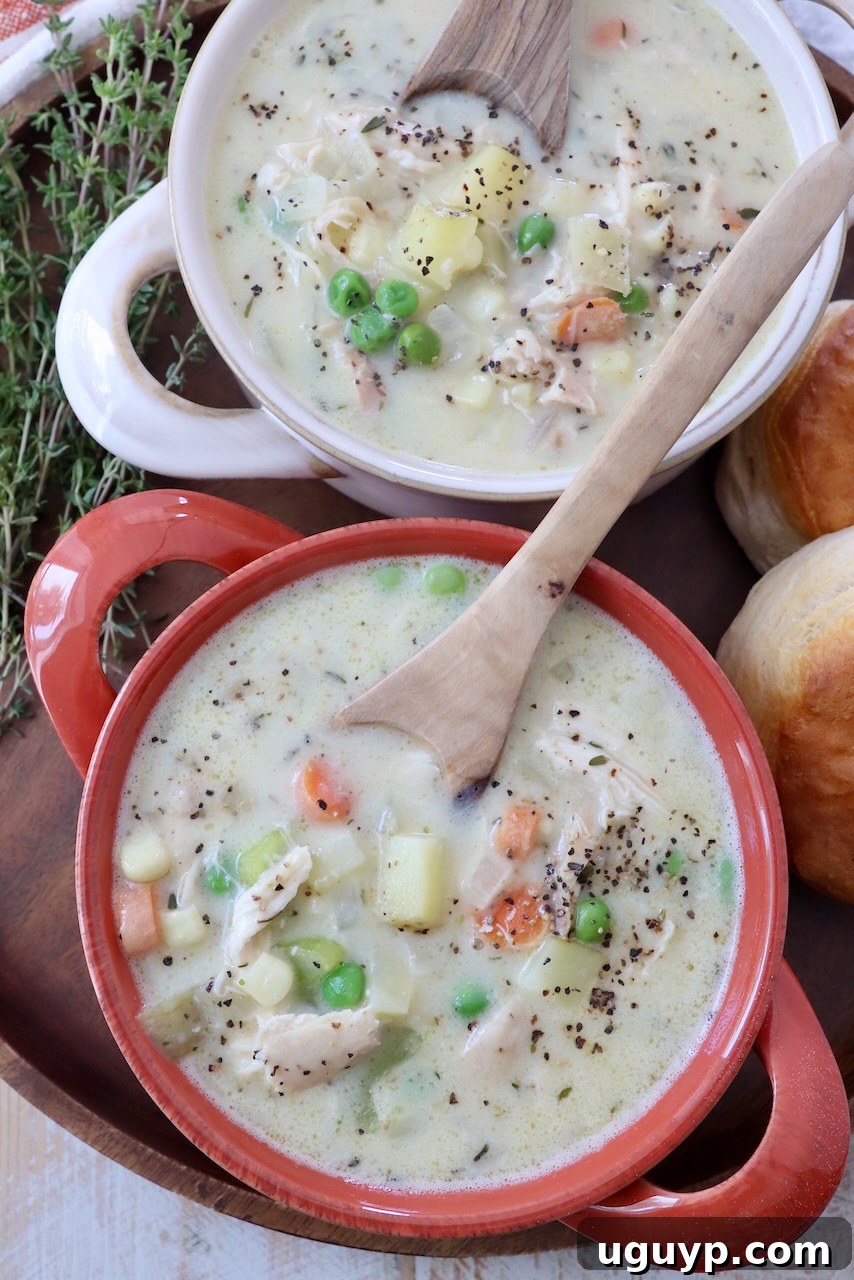 Two inviting bowls of creamy chicken pot pie soup with spoons, ready to be enjoyed.