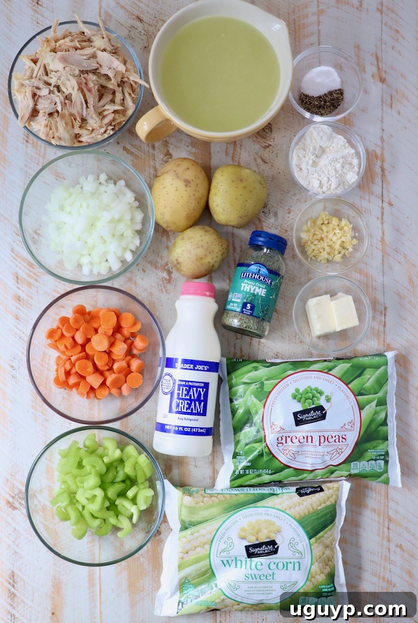 Fresh ingredients laid out for making chicken pot pie soup: butter, carrots, onions, celery, garlic, flour, chicken broth, thyme, salt, pepper, Yukon gold potatoes, cooked shredded chicken, frozen peas, frozen corn, heavy cream.