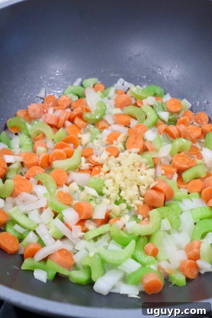 Finely diced carrots, onions, celery and minced garlic sautéing in a skillet