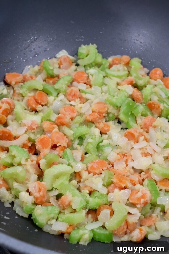 Golden brown flour combined with diced vegetables in a large skillet, forming a roux