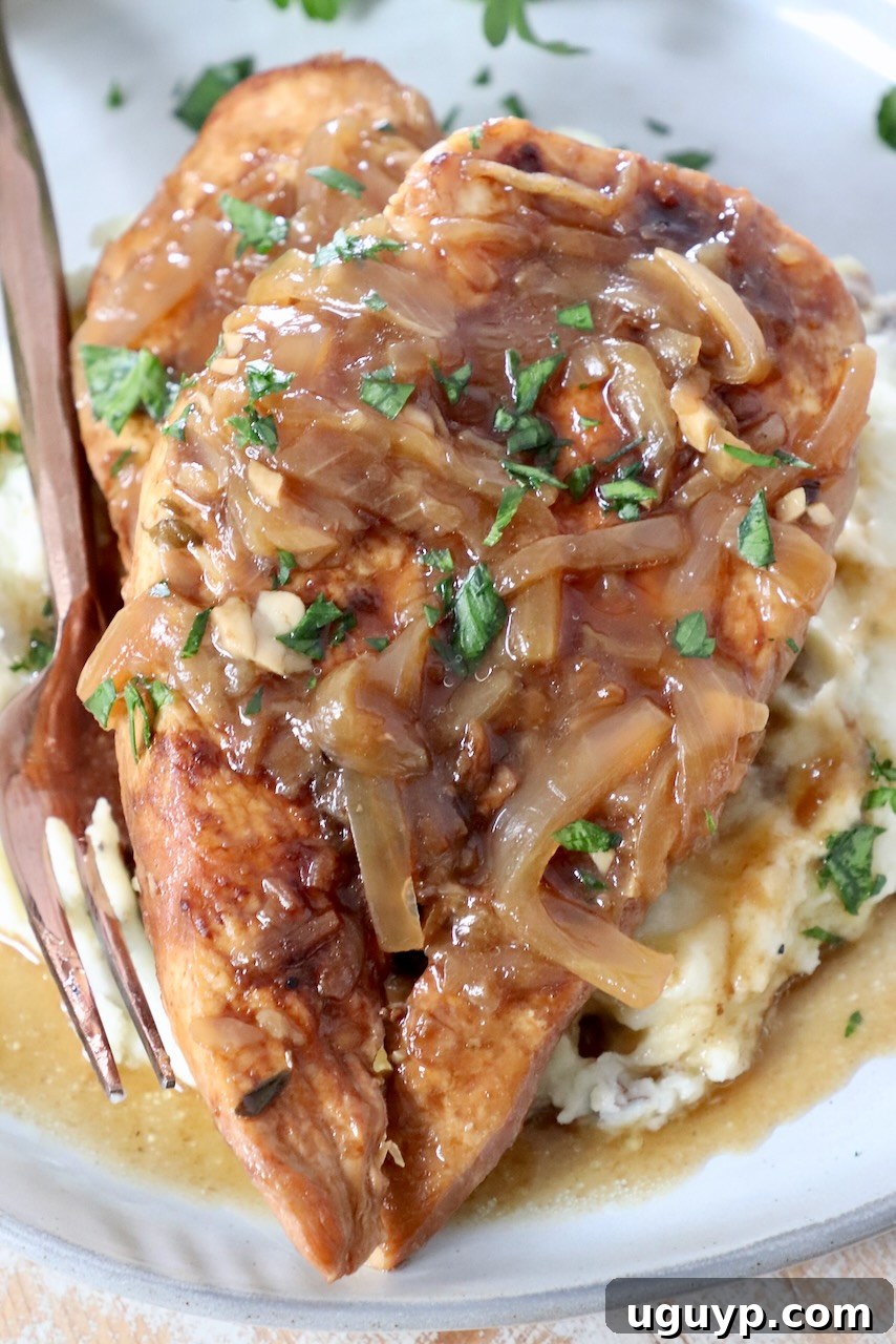 cooked chicken breasts on plate with caramelized onion gravy