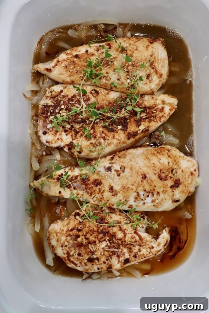 seared chicken breasts in slow cooker with fresh thyme sprigs and caramelized onions