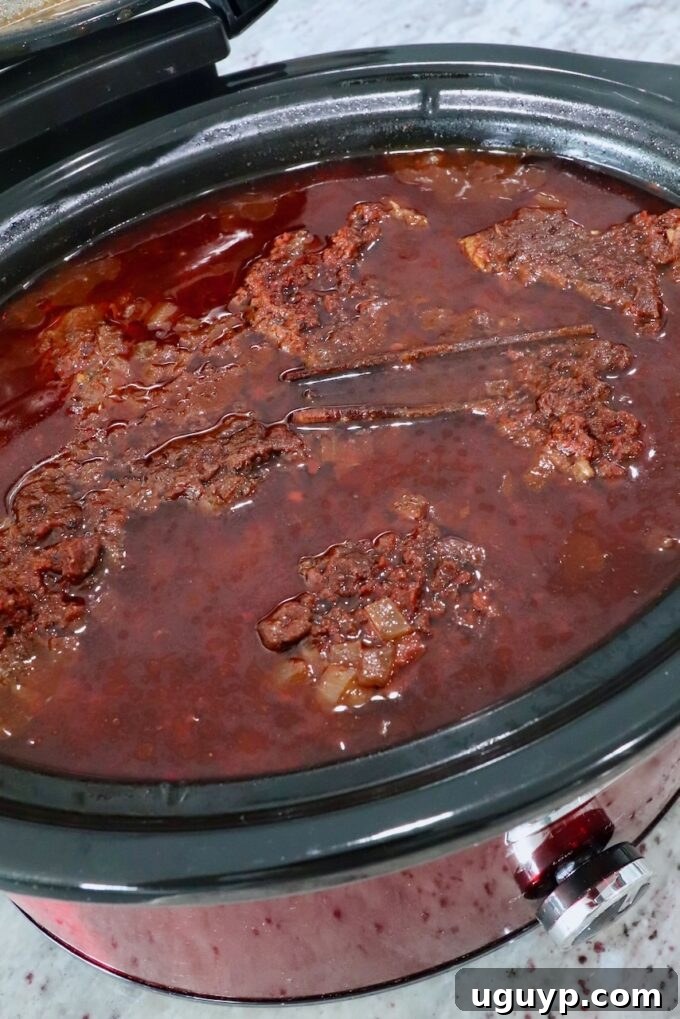 cooked birria in a slow cooker, ready to be shredded