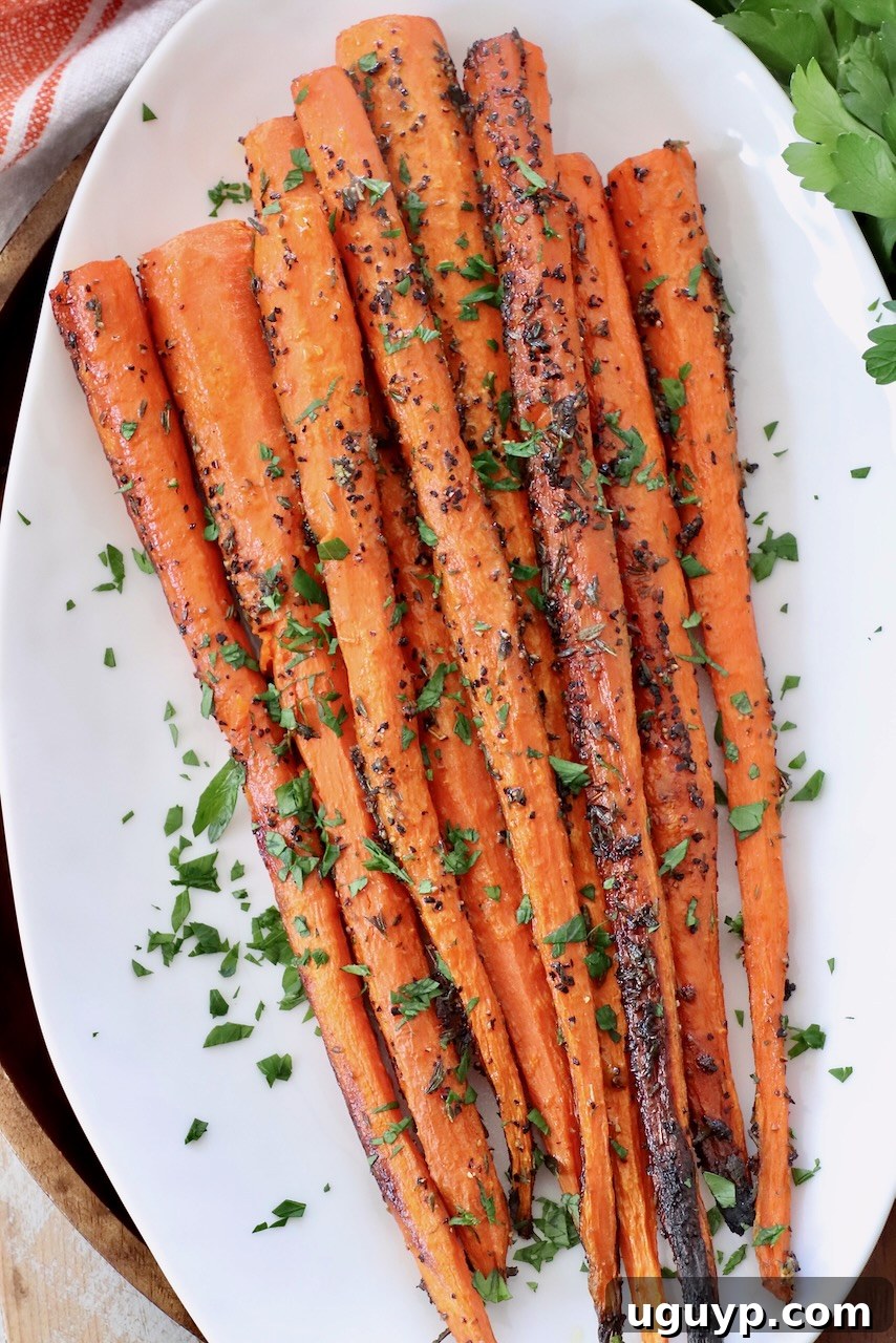 Roasted carrots topped with fresh chopped parsley on a white plate, highlighting their beautiful char and vibrant green garnish.
