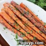 Roasted carrots on plate topped with fresh chopped parsley, ready to be served.