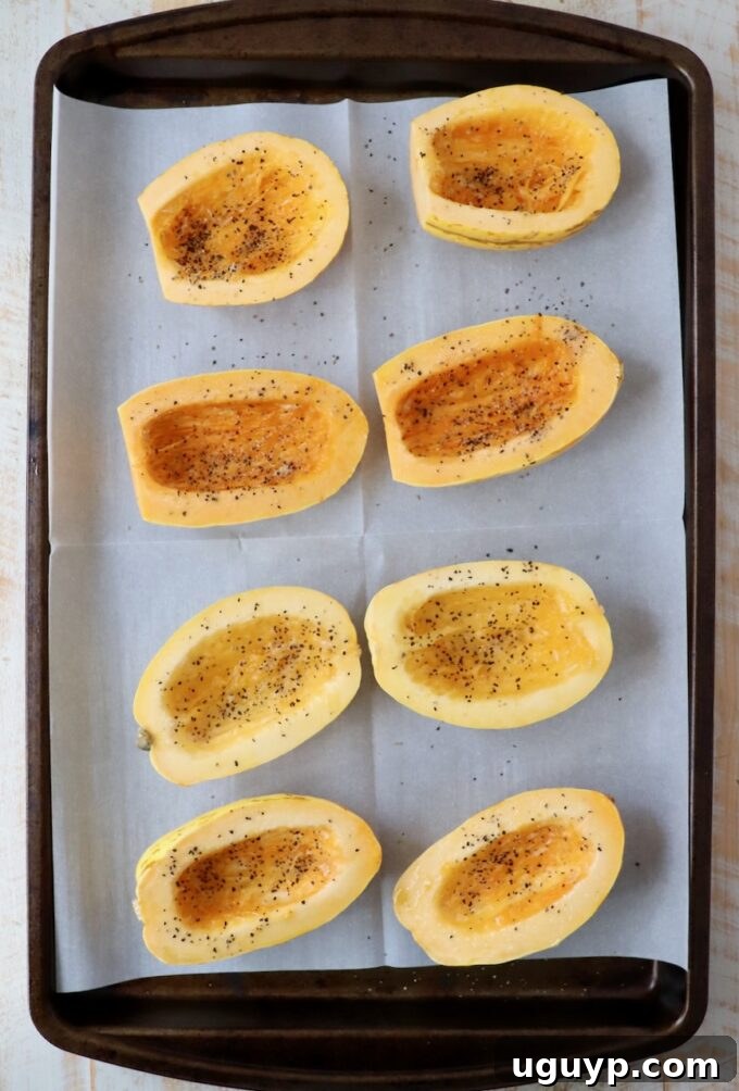 delicata squash sliced in half and seasoned on baking sheet