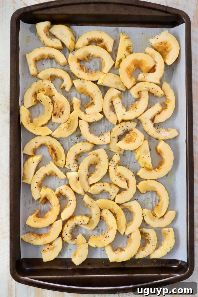 sliced pieces of delicata squash on baking sheet