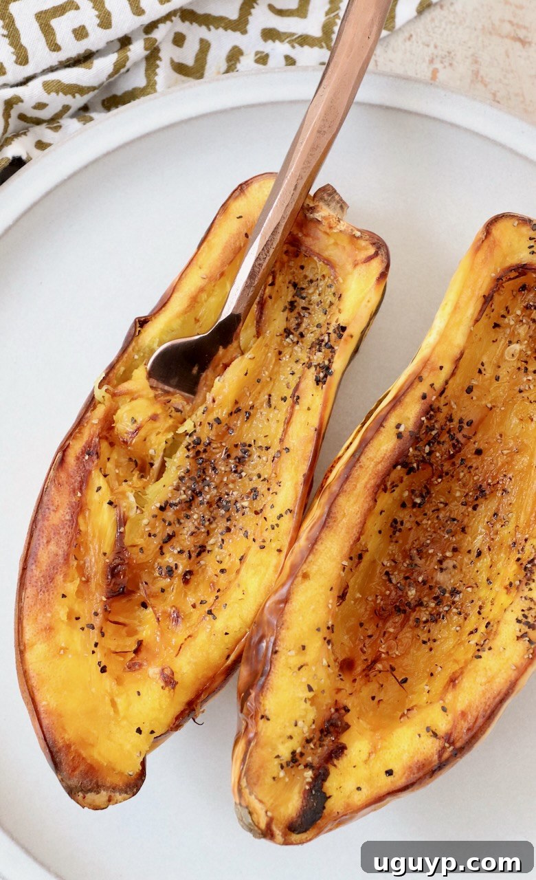 cooked delicata squash cut in half on plate with fork