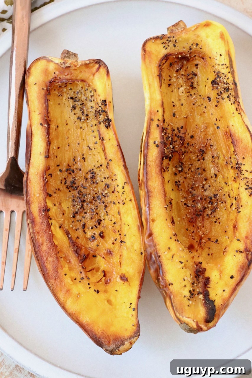cooked delicata squash cut in half on plate with fork