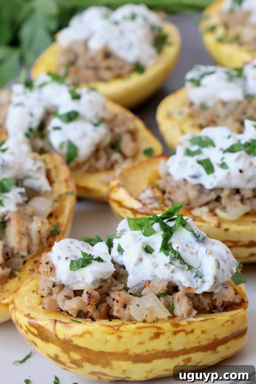 Two halves of roasted delicata squash, richly stuffed with seasoned chicken sausage and creamy herb ricotta, beautifully presented on a plate, ready to be enjoyed as a hearty fall meal.