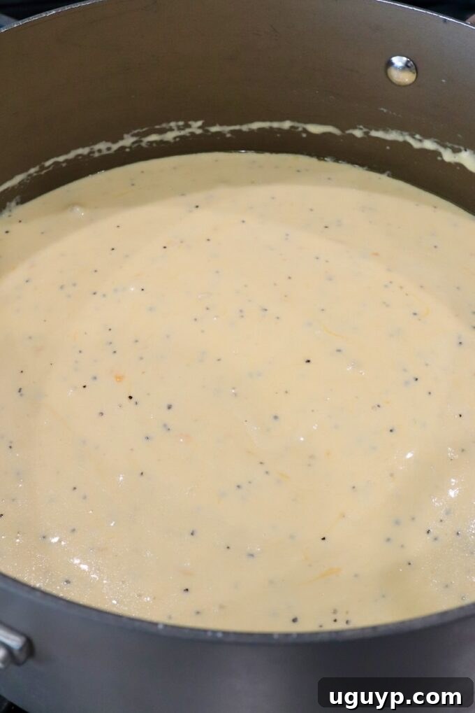 A large pot filled with a rich, creamy, and golden cheese sauce, ready for the macaroni noodles to be incorporated.