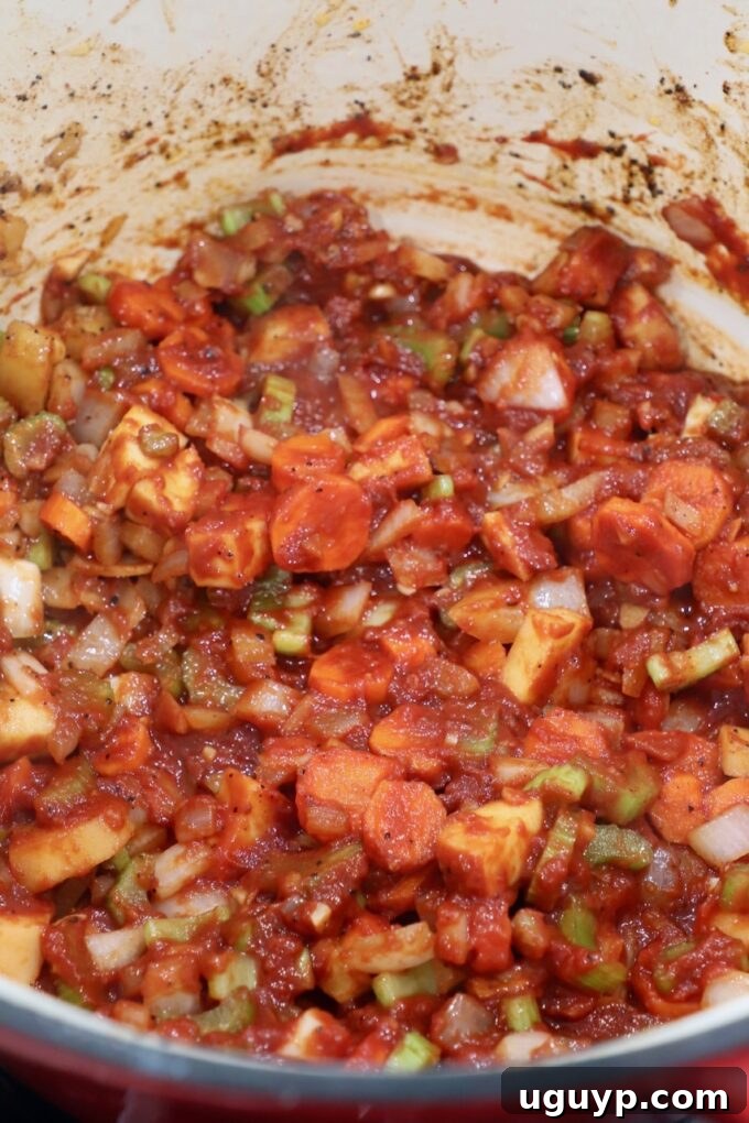 Sautéed diced vegetables mixed with tomato paste in a Dutch oven, deepening in color and flavor.
