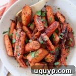 Roasted honey glazed carrots in bowl with spoon, ready to serve.