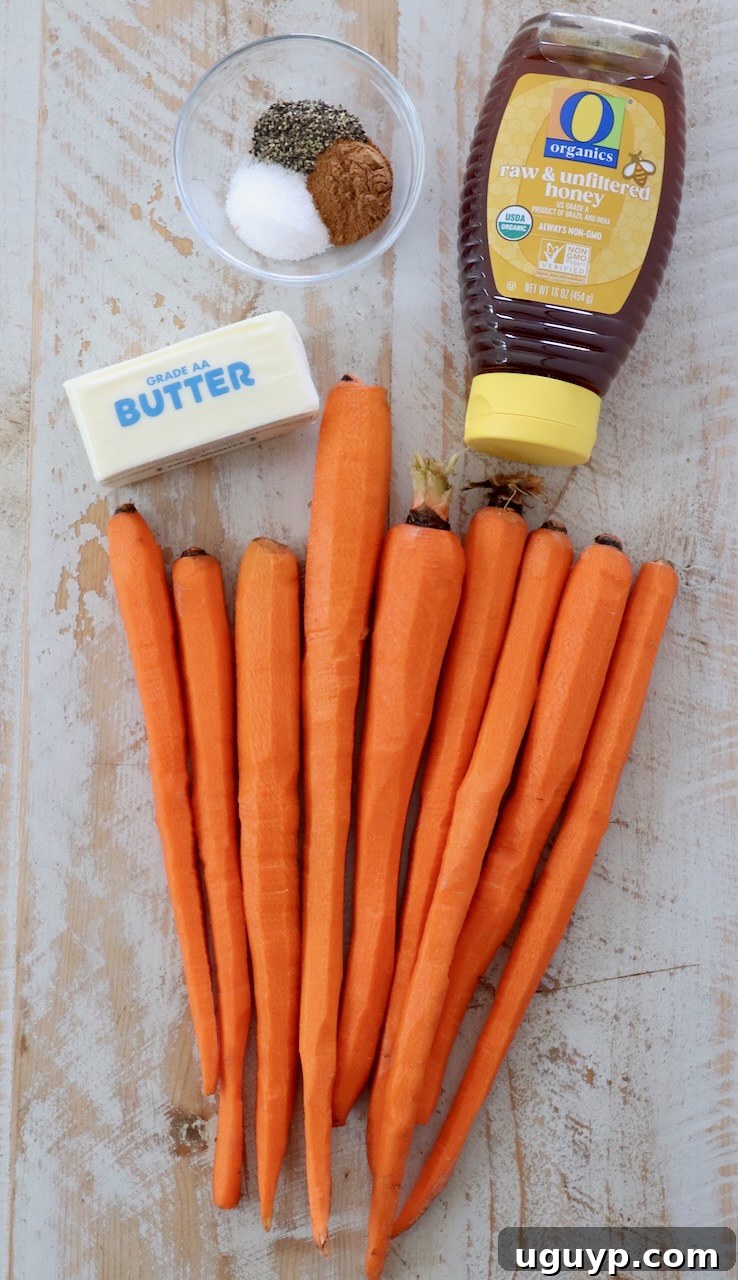 Individual ingredients for honey glazed carrots laid out on a white wooden board, including fresh carrots, honey, butter, and spices.