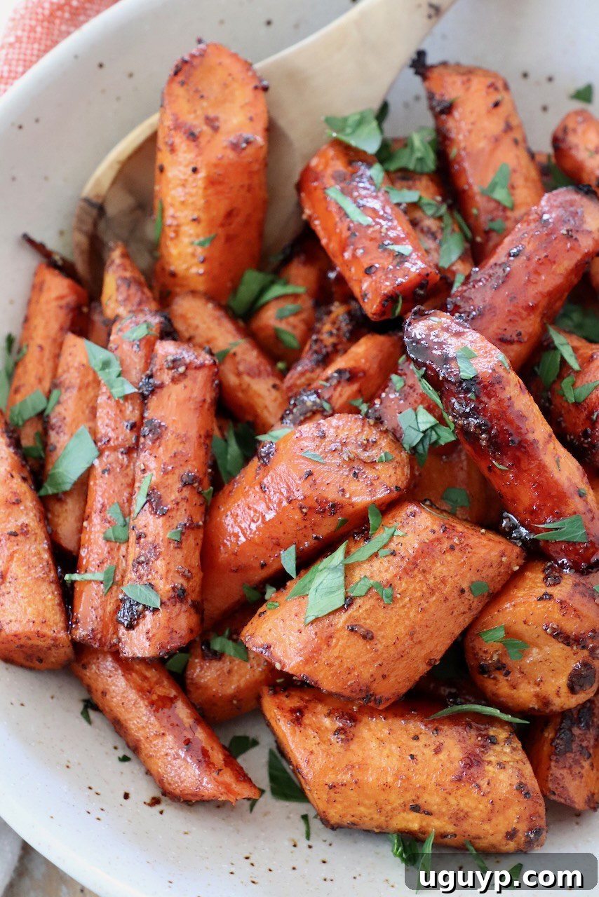 Sliced honey glazed roasted carrots in a white bowl with a serving spoon, ready to be enjoyed.
