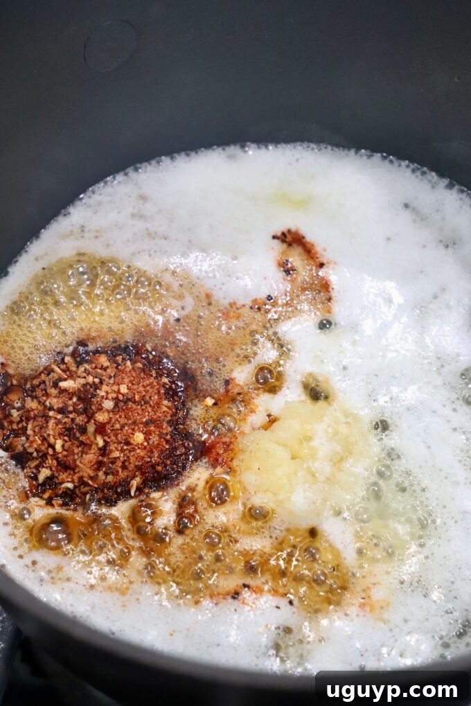 Lemon juice, crushed garlic, and steak seasoning added to melted butter in a saucepan