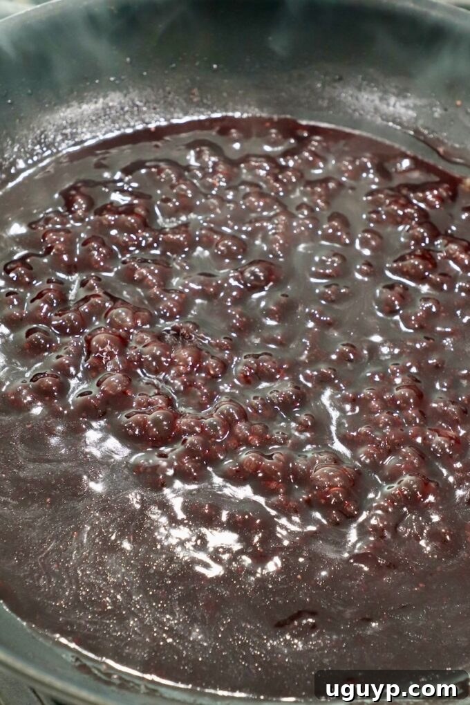 Reduced and thickened red wine sauce in a skillet, garnished with fresh thyme.